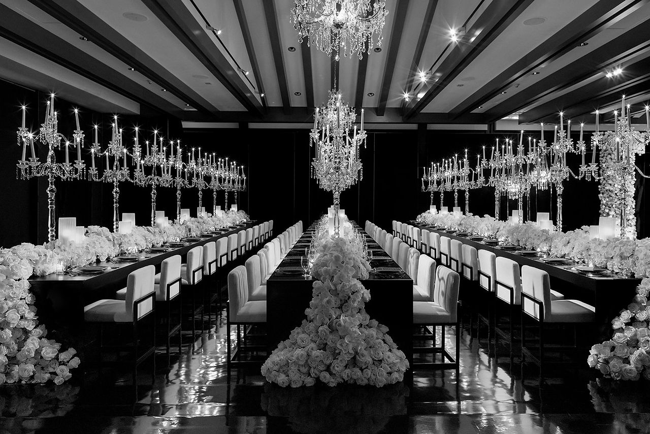 Black and white wedding dining setup with crystal chandeliers