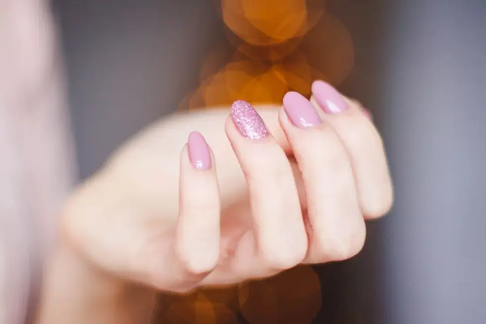 Närbild på glitter naglar i rosa med inbäddade flak
