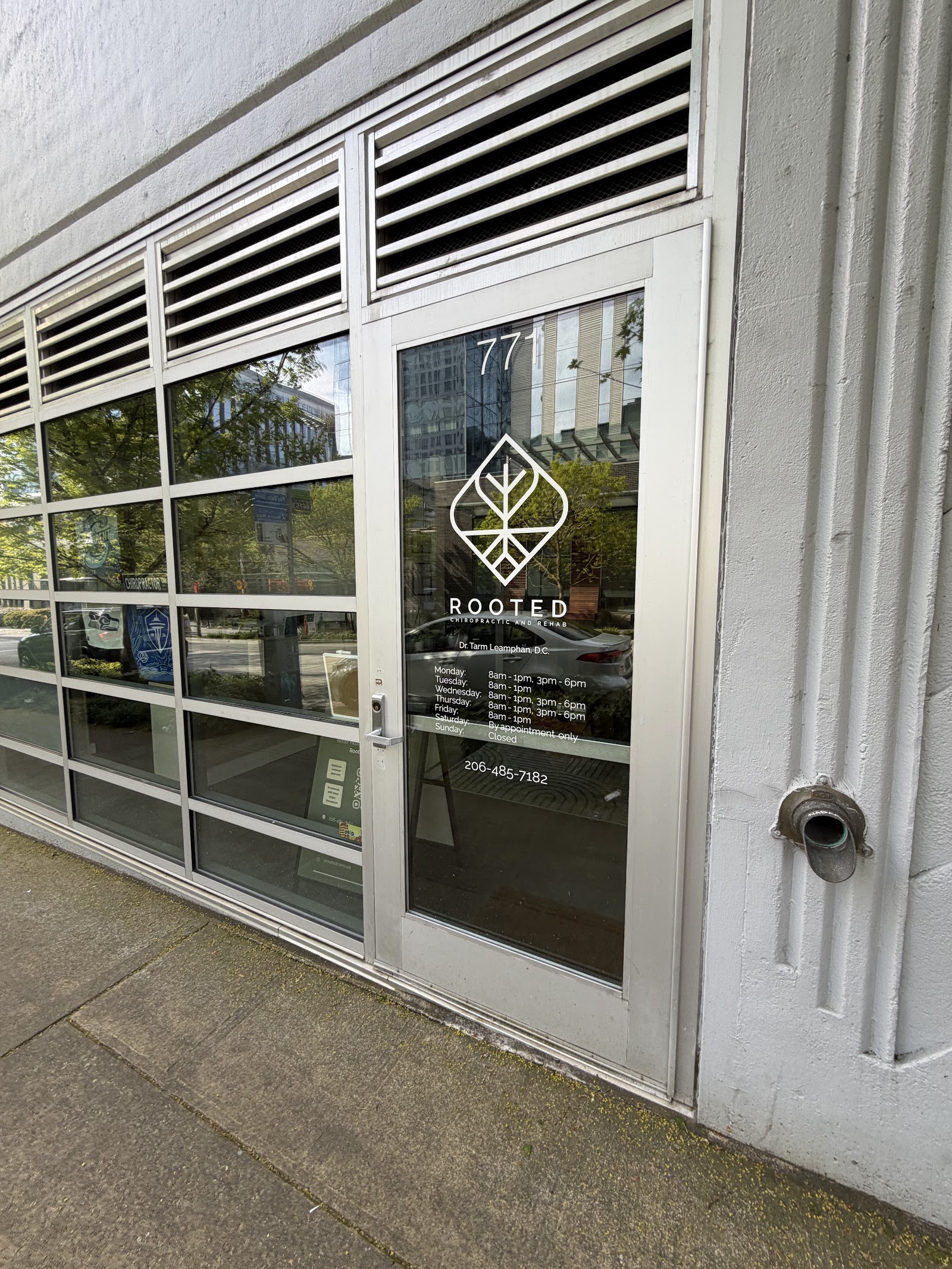 Storefront exterior with glass door showing the '77' street number and ROOTED leaf-logo decal, 771 Thomas St