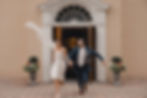 bride and groom running out of door smiling