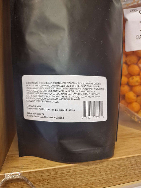 Black bag with label including ingredients and barcode on wooden shelf background.