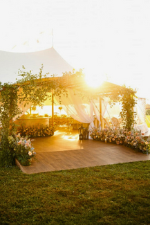 tented wedding reception adorned in flowers at sunset