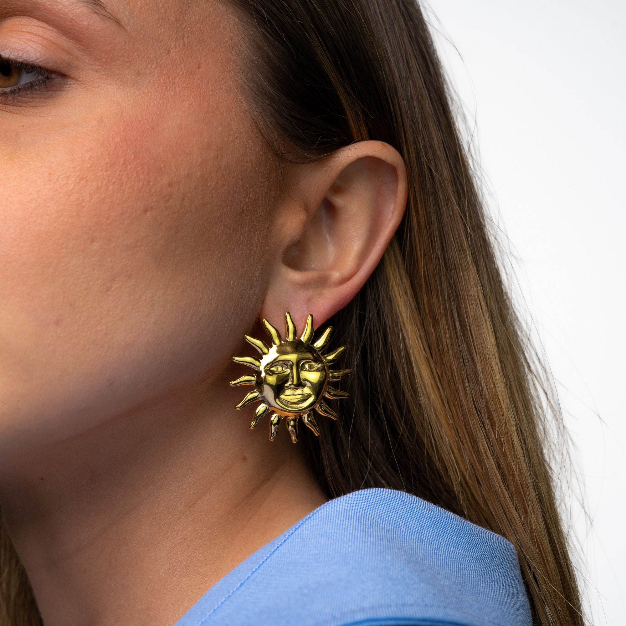 Boucles en formes de soleil portées avec une chemise bleue