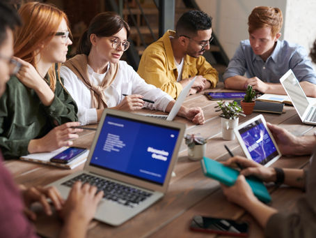 A group of people in a meeting with laptops