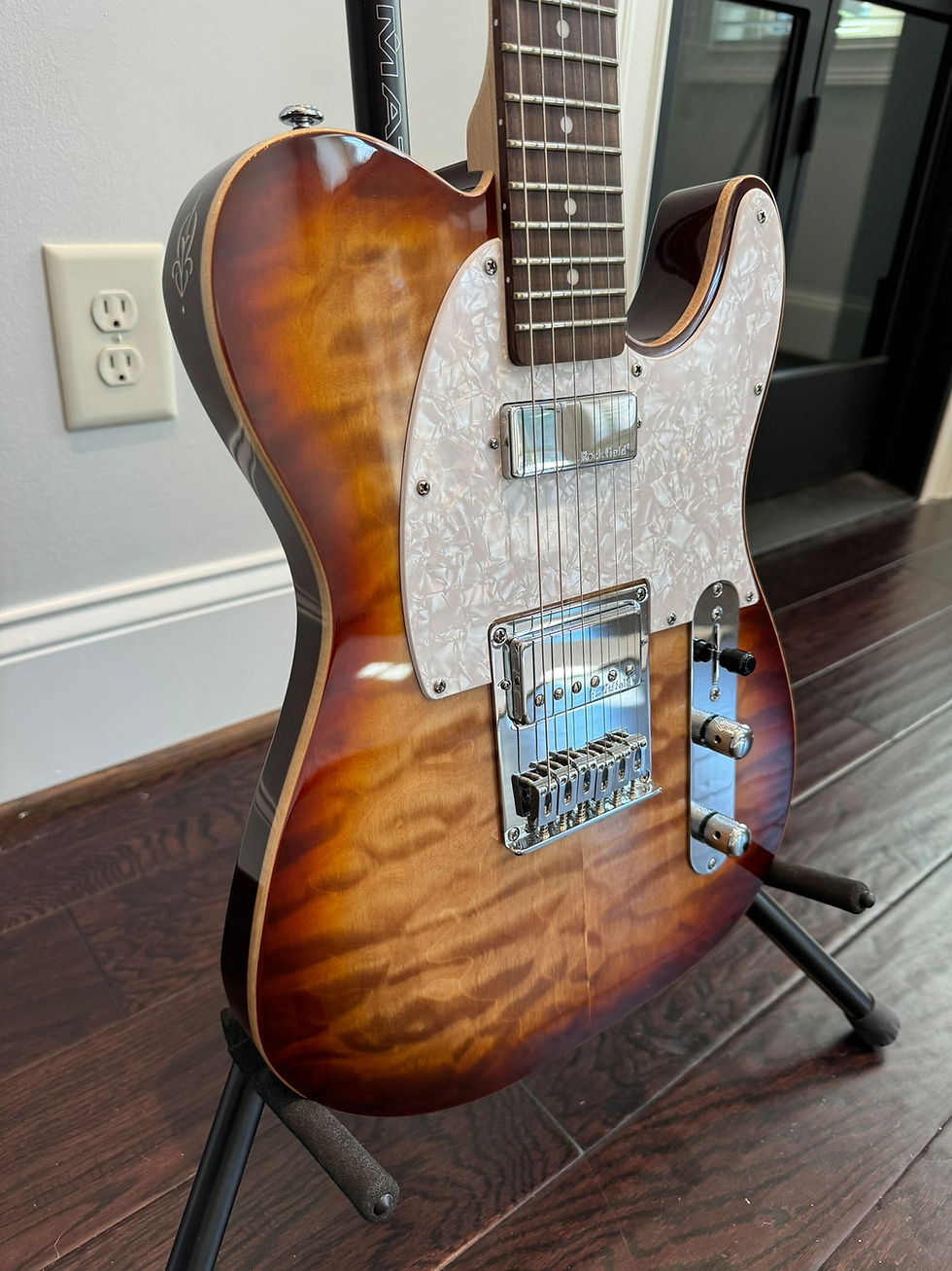 Telecaster-style electric guitar with sunburst finish, pearloid pickguard on stand.