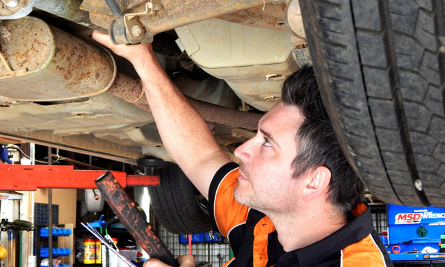 Speedy Spanners mechanic working under a vehicle on the hoist