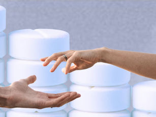 Twee handen die elkaar bijna raken boven een achtergrond met witte tabletten, als symbool voor shared decision making bij opiaten afbouwen.