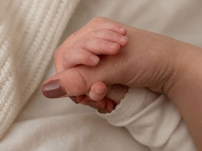 Pasgeboren baby houdt de vinger van haar moeder vast