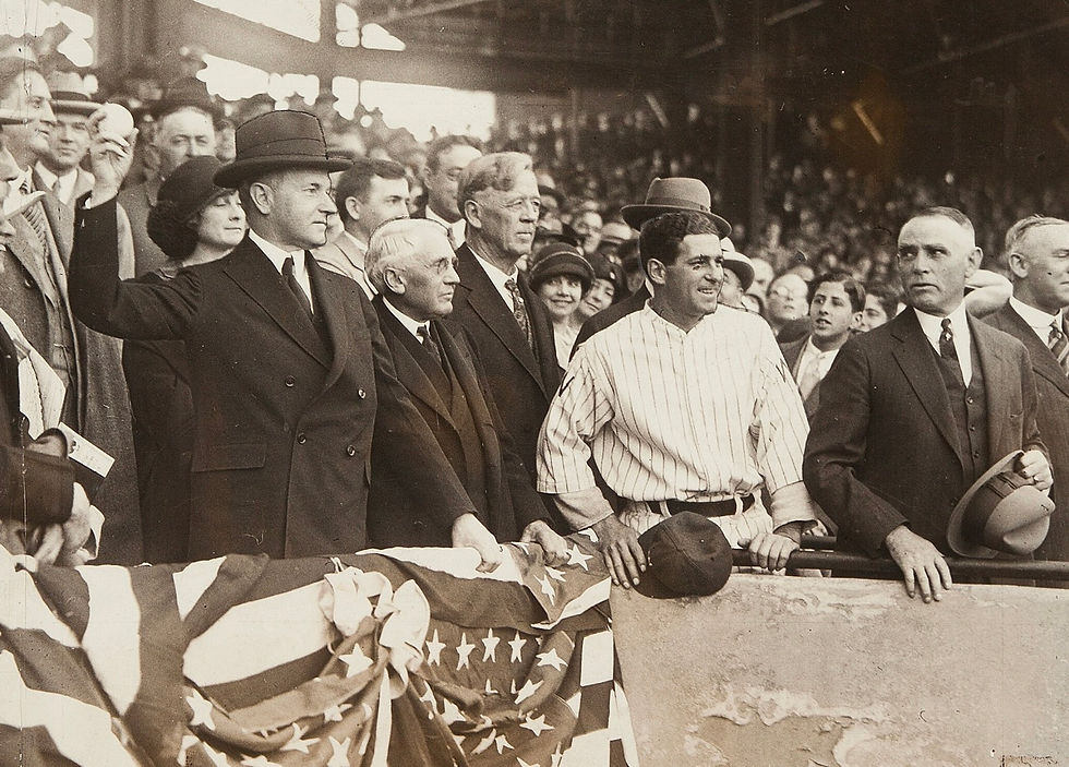 Black-and-white photo of President Calvin Coolidge throwing out a first pitch at a baseball game in 1925, surrounded by spectators.