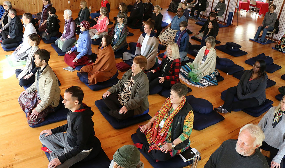 People sitting on cushions meditating in a group, practicing mindfulness exercises.
