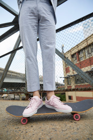 Man in a blue suit and pink sneakers standing on a skateboard in an urban setting.
