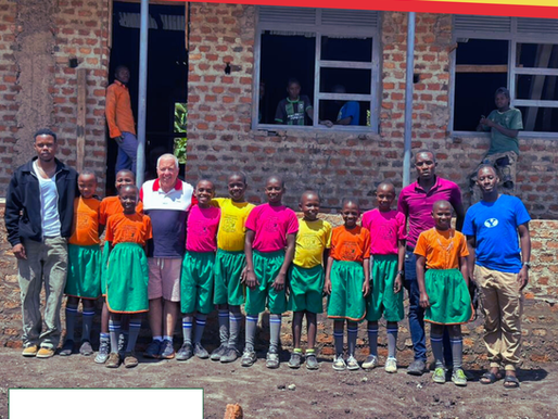 Mr. Chairman Martyn David Crespel TEP, with sponsored children standing against a newly constructed classroom
