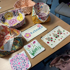 A selection of brightly coloured fabric baskets and zipped pouches. All the items are made from fabric hand printed with stylised flowers and leaves.