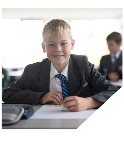A teenage boy in school uniform smiling and looking directly at the camera and holding a pencil to draw with