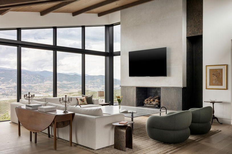 Living room with fireplace, modern furnishings, and expansive mountain views in the Axis residence