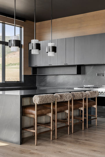Kitchen island with dark cabinetry, stone countertop, and leather stools in Eagle’s Nest