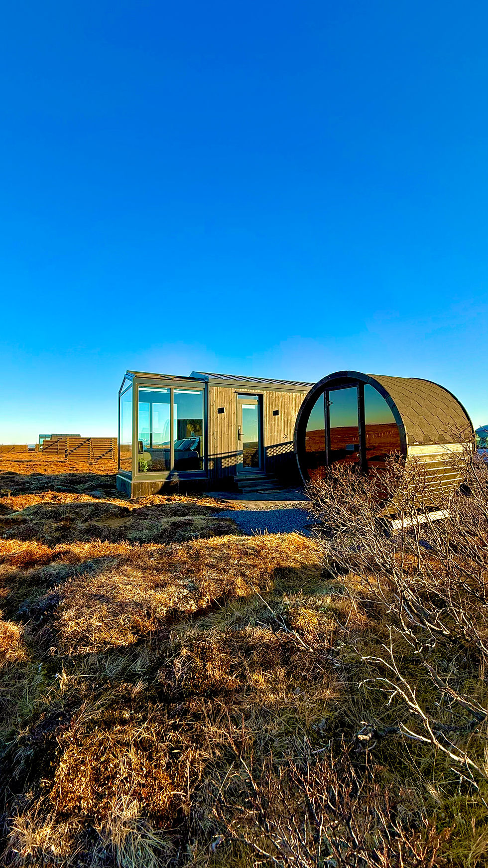 Wide angle view of a glass lodge exterior nestled in a rugged Icelandic landscape