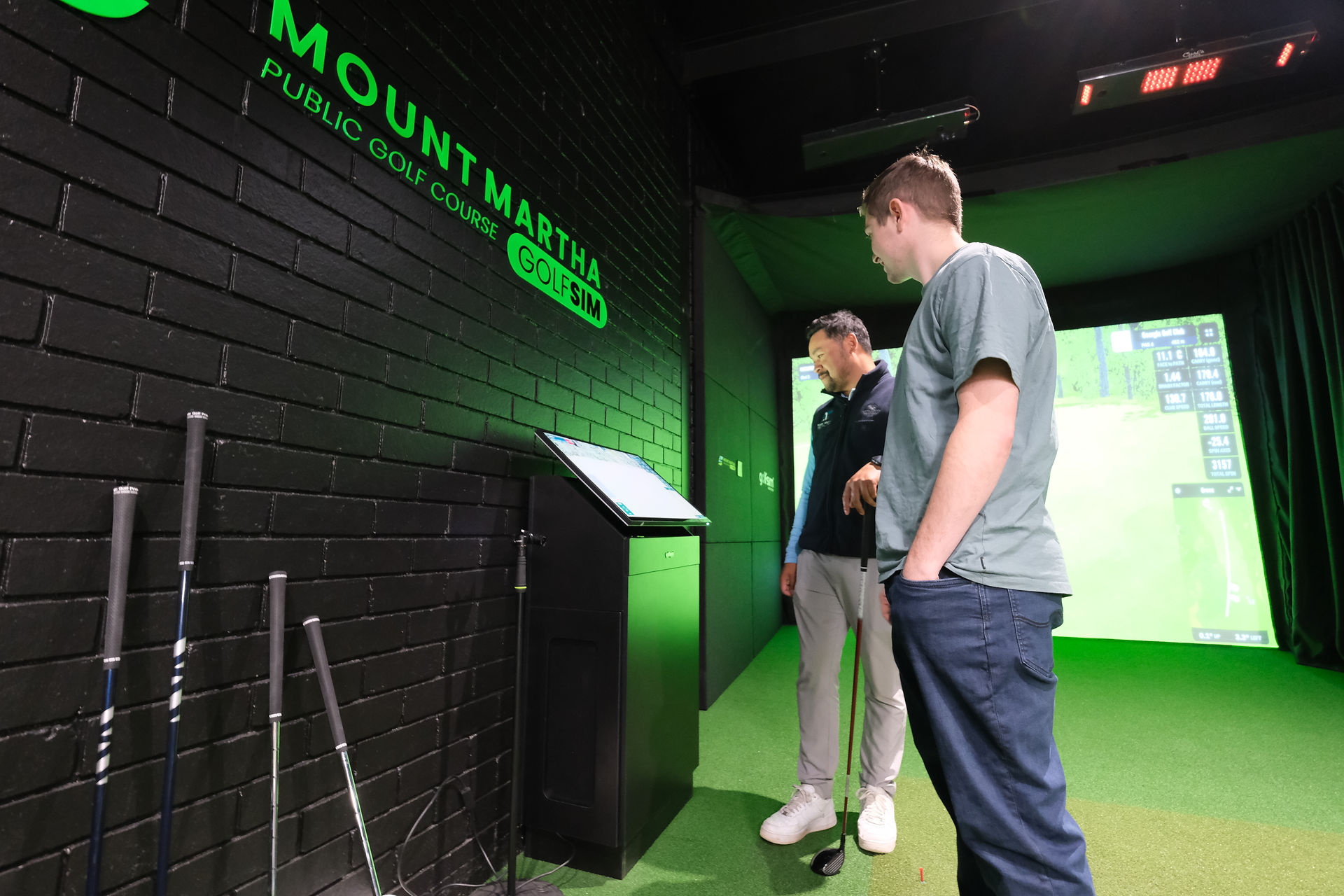 Two people standing in front of Golfsim Australia commercial simulator at Mount Martha Public Golf Course.