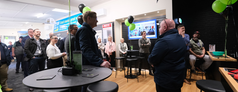 Guests gathered in the Mt Martha GolfSim lounge area during the grand opening event, surrounded by green balloons and high-top tables in a modern clubhouse setting.