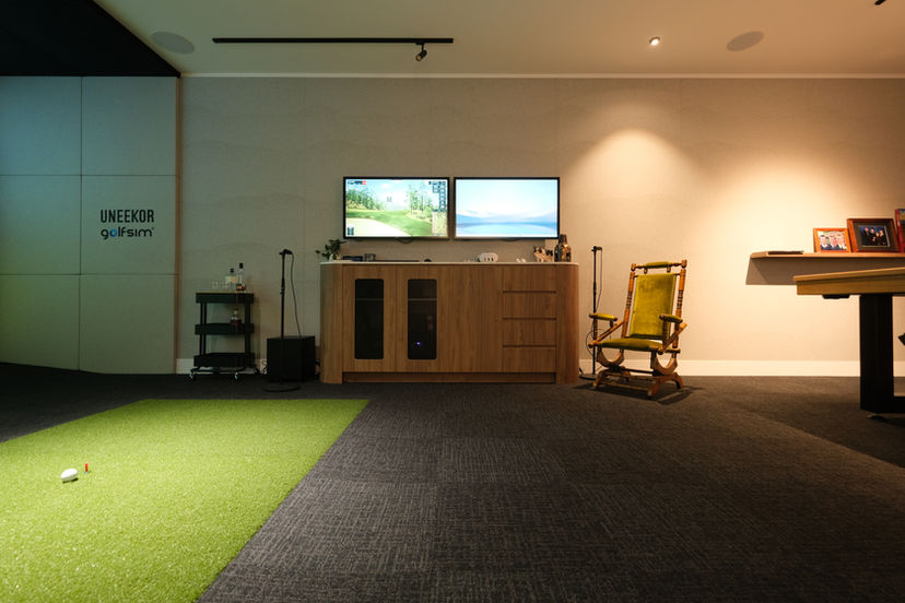 Minimalist home simulator space with GSPro dual screens, Uneekor tracking, putting green, and pool table — designed by Golfsim Australia.