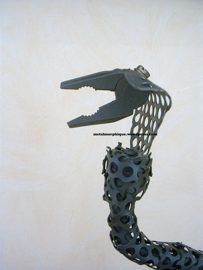 Sculpture en métal d'un serpent (cobra), vue zoomée des détails de sa tête avec la gueule ouverte et du haut de son corps