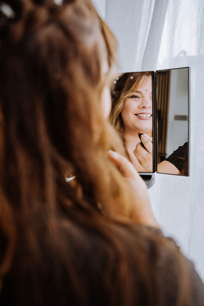 Braut schaut beim Getting Ready in den Spiegel – Hochzeit in Mitterteich