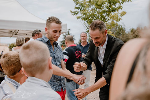 Un magicien fait un tour de magie ) un homme, ils sont souriants, et l'ambiance générale de la photo est très positive