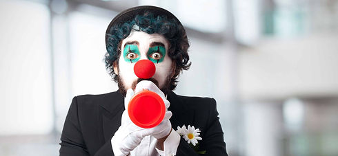 Un homme déguisé en clown tient un "pouet pouet" dans ses mains