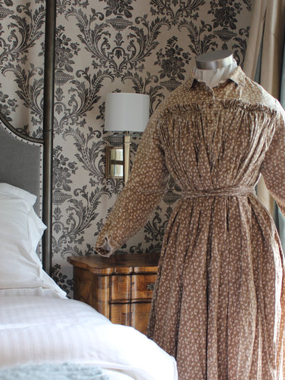 A dress is displayed on a mannequin in the setting of an elegant bedroom