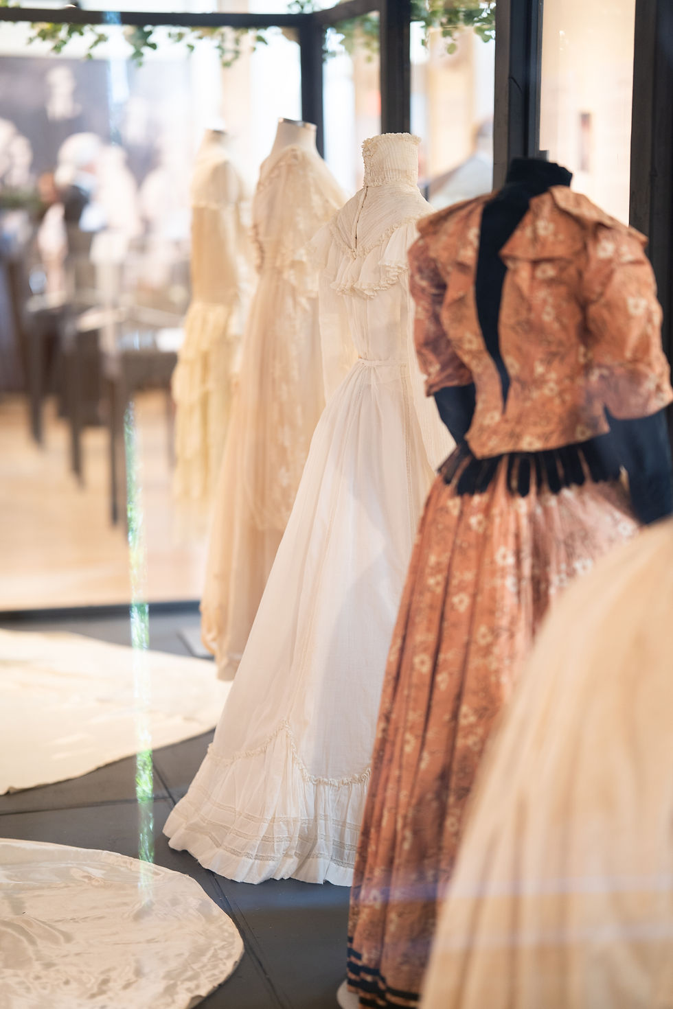 photograph of the backs of four wedding dresses in a display case