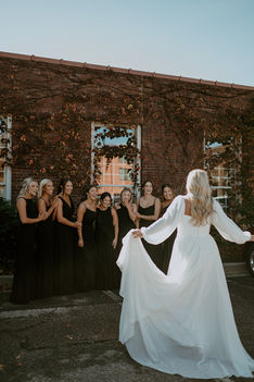 Bride doing a first look with bridesmaids by the brick exterior of the downtown wedding venue The Vail in Wichita KS