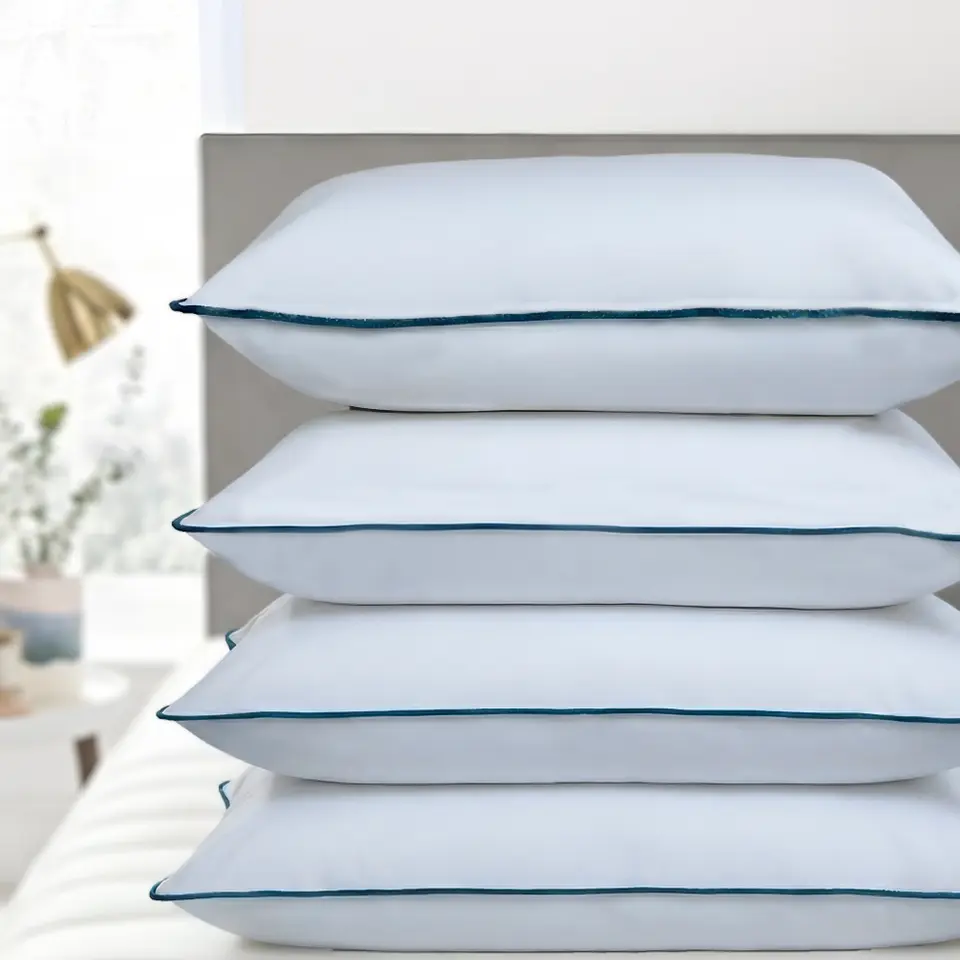 Stack of four white SILICON BALL Fiber Pillows on a bed, showing the smooth cotton cover and piped edges.