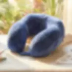 Angled view of the plush VISCO MEMORY TRAVEL Neck Pillow resting on a bed, highlighting its contoured neck support