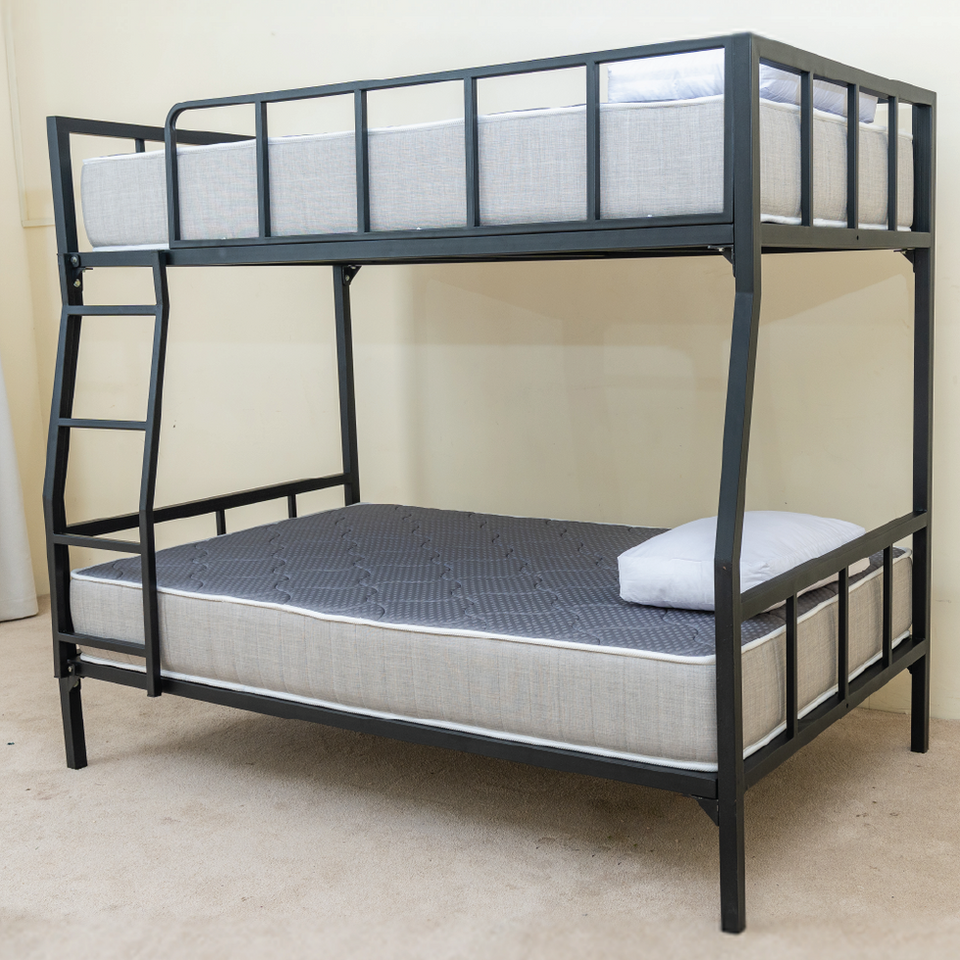 Angled view of the black metal DrM Furniture BUNK bed with Barrier featuring a side ladder.