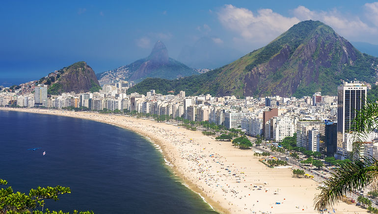 White sand beach in front of green towering hills in Rio de Janeiro