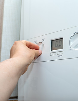 A hand adjusting the temperature knob on a household boiler with digital display Concept o