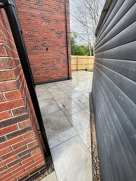 natural-stone-patio-narrow-walkway-grey-tiles-brick-wall.jpeg