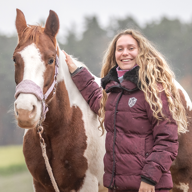 Tiertherapeutin mit Pferd bei der physiotherapeutischen Bodenarbeit auf dem Reitplatz, Fokus auf vertrauensvoller Verbindung