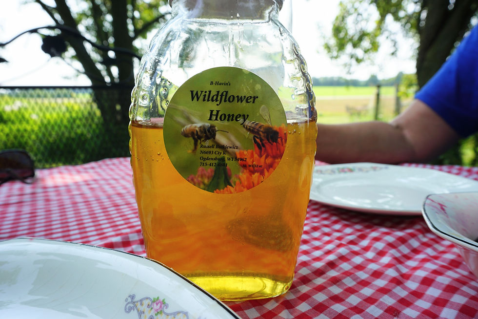 A jar of honey sits on a table with a red gingham table cloth.