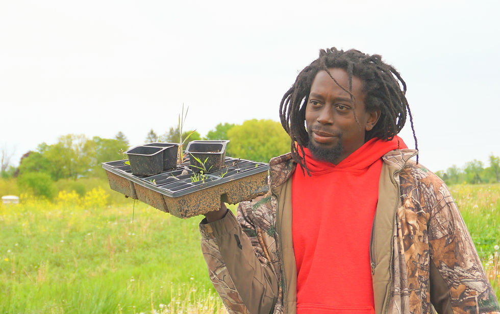 Martice stands in a green field and holds containers for planting.
