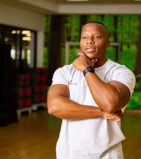 Coach Wes looking thoughtfully in a gym setting with wooden floors and background