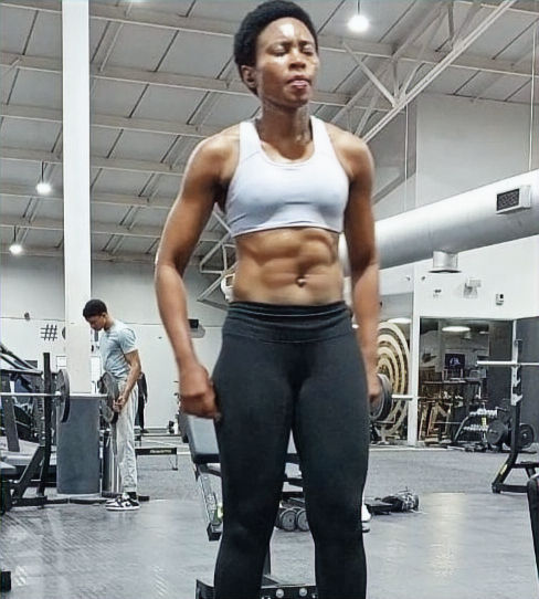 Fit woman with defined abs in gym setting Core Conditioning group.