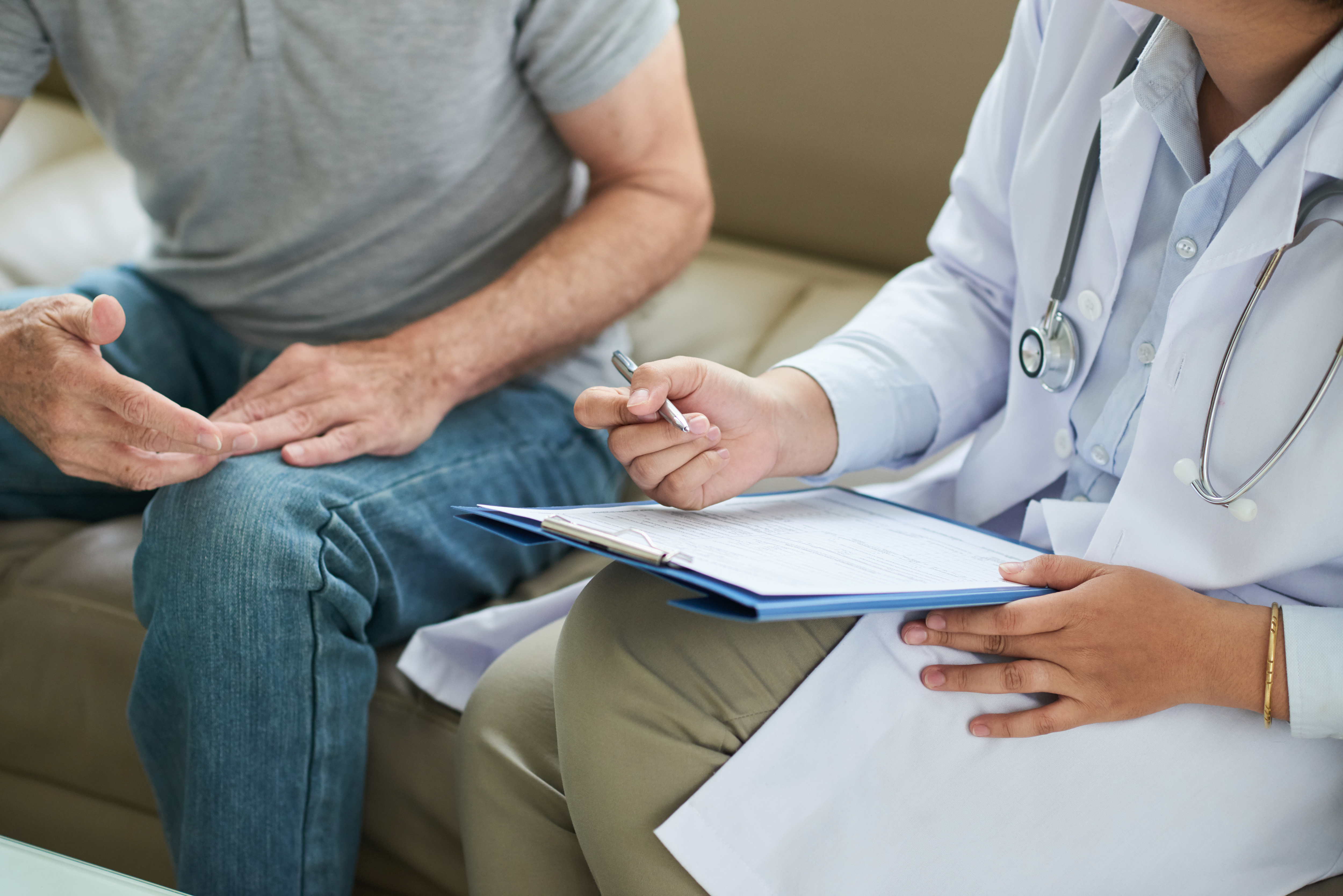 unrecognizable-female-doctor-sitting-couch-with-male-patient-filling-form.jpg