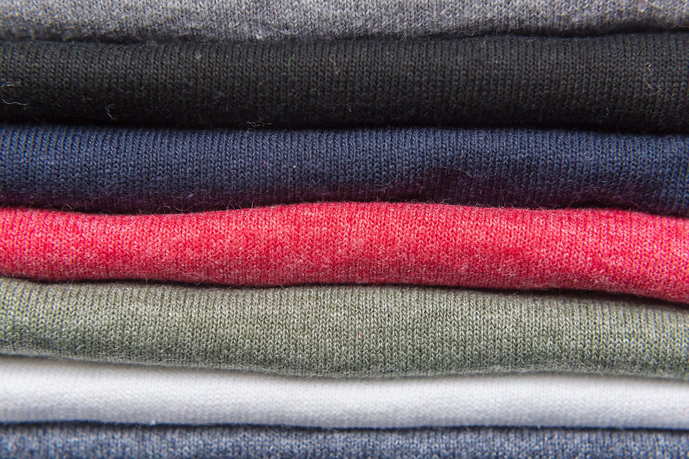 A neatly folded stack of plain T-shirts in different colors.