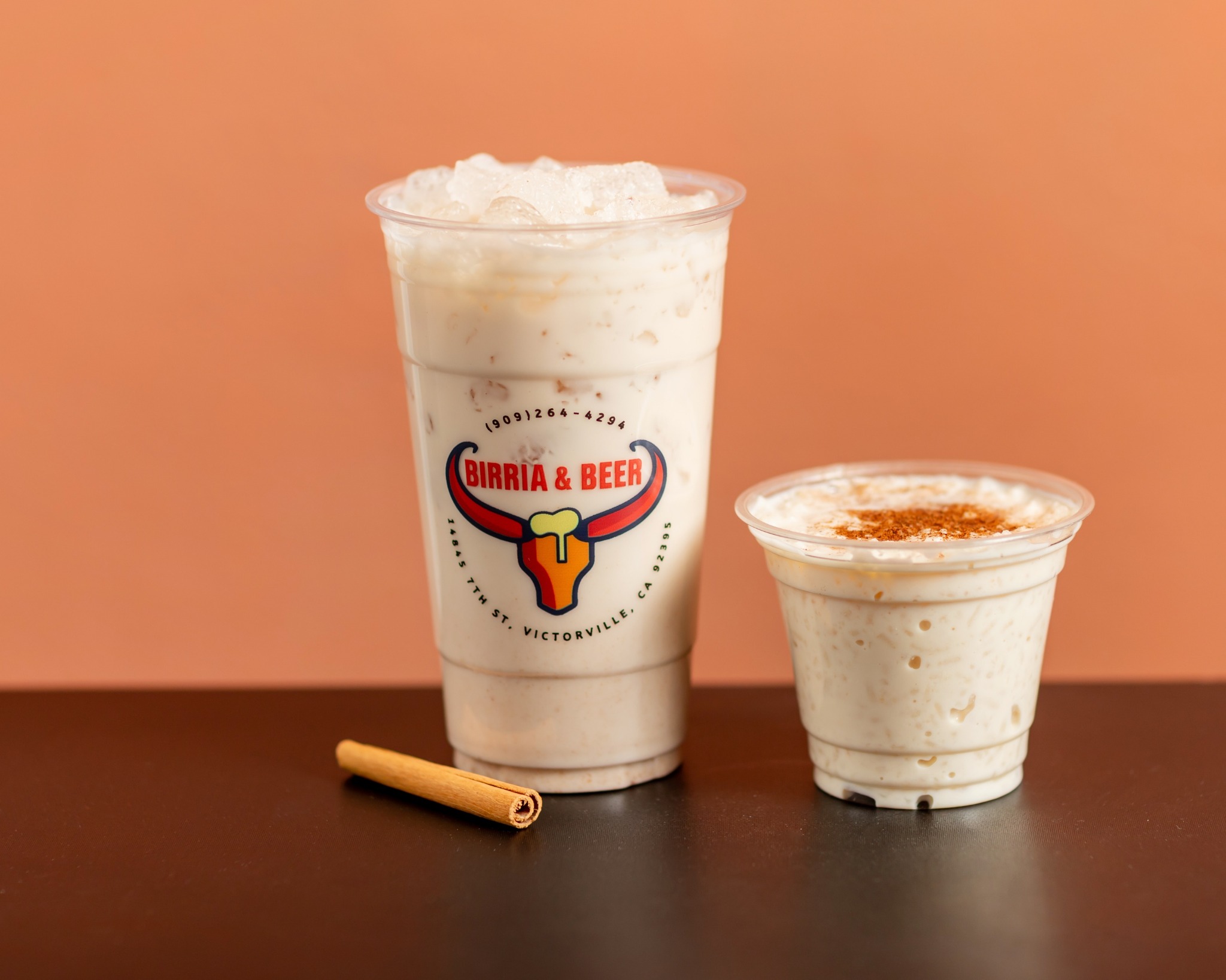 Two cups of horchata with cinnamon and original Birria & Beer branding