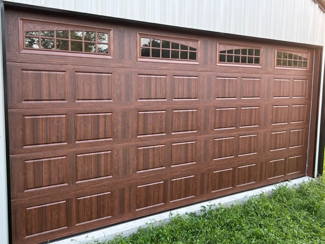 New garage door installation. Walnut woodgrain finish garage door withwindows.