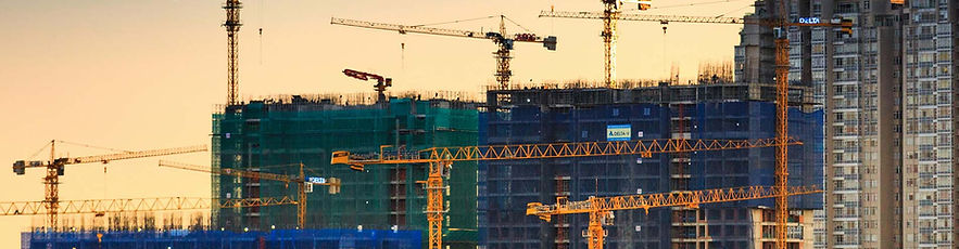 large building being built with cranes at sundown