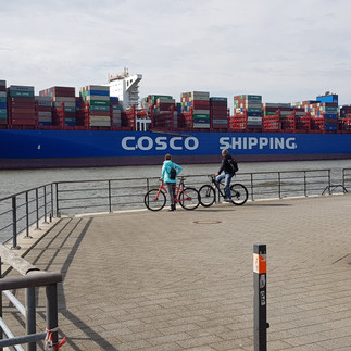 Zwei Radfahrer vor Cosco Shipping Frachtschiff in Hamburg