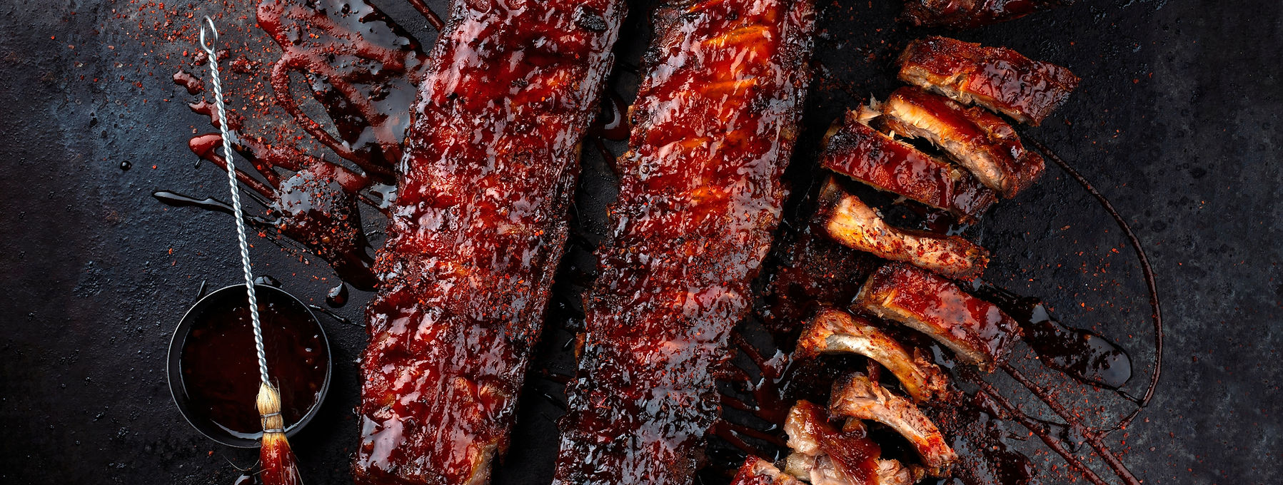 Barbecue spare ribs St Louis cut with hot rub and BBQ sauce as closeup on a black board.jp