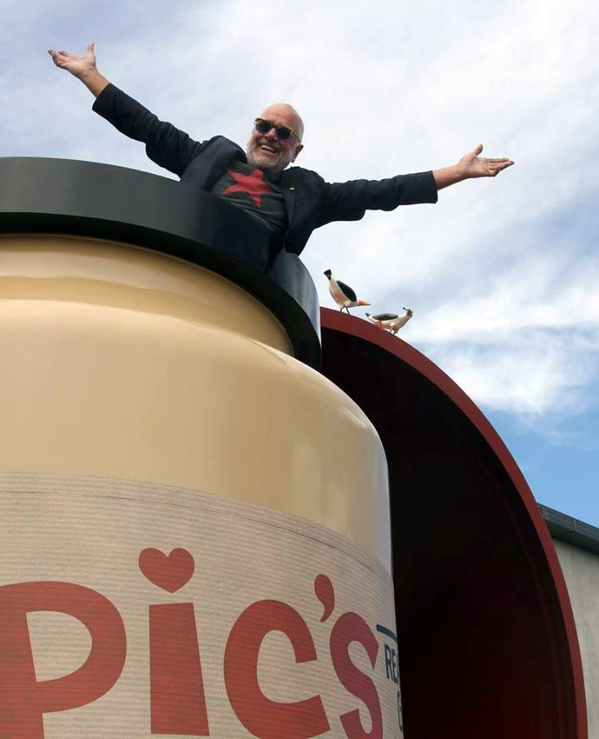 Pic Picot, founder of Pic's Peanut Butter, standing on top of the giant Pic's jar outside Peanut Butter World in Nelson, New Zealand